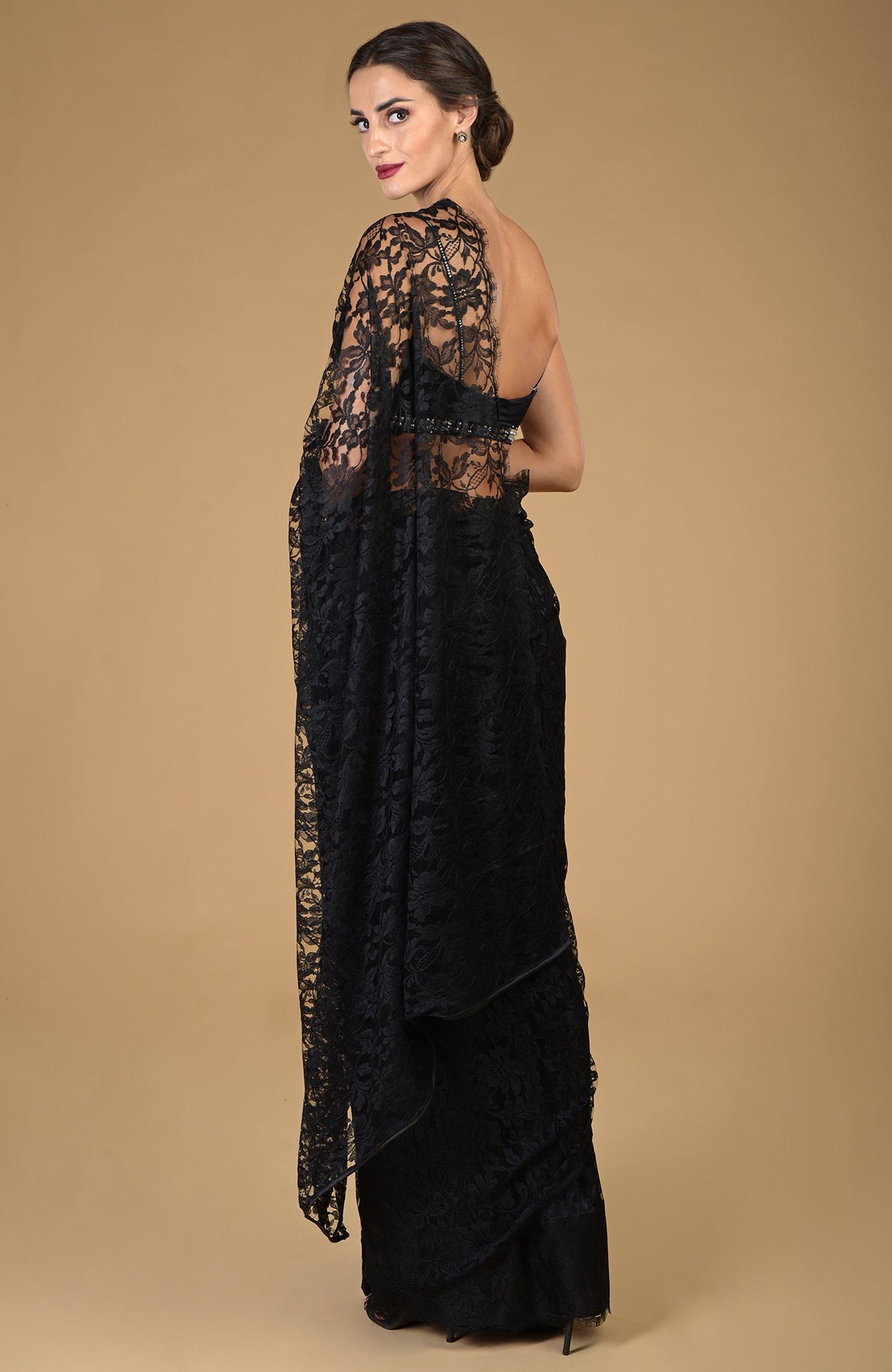 A woman models a black French Chantilly lace saree with an embellished blouse.