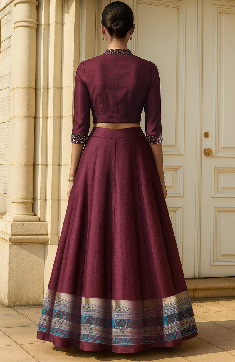 Deep wine lehenga set with silver embellishments, cropped blouse, and ornate printed skirt hem.