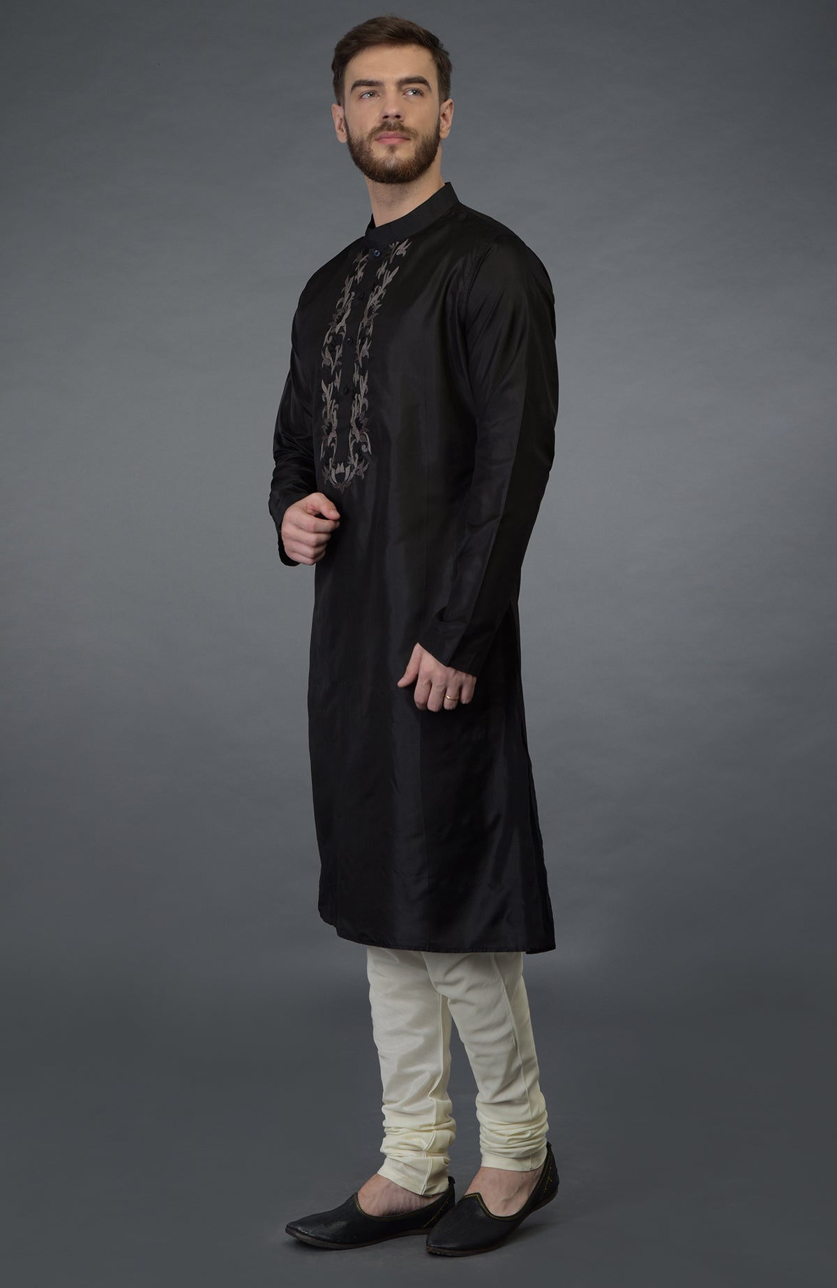 Black silk kurta with floral embroidered placket detail, paired with cream churidar and black juttis.