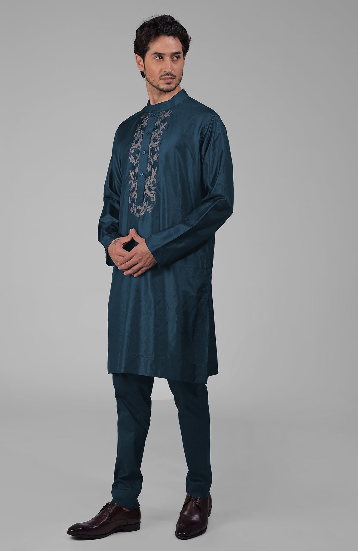 Teal silk kurta with floral embroidered placket detail, paired with matching pants and brown shoes.