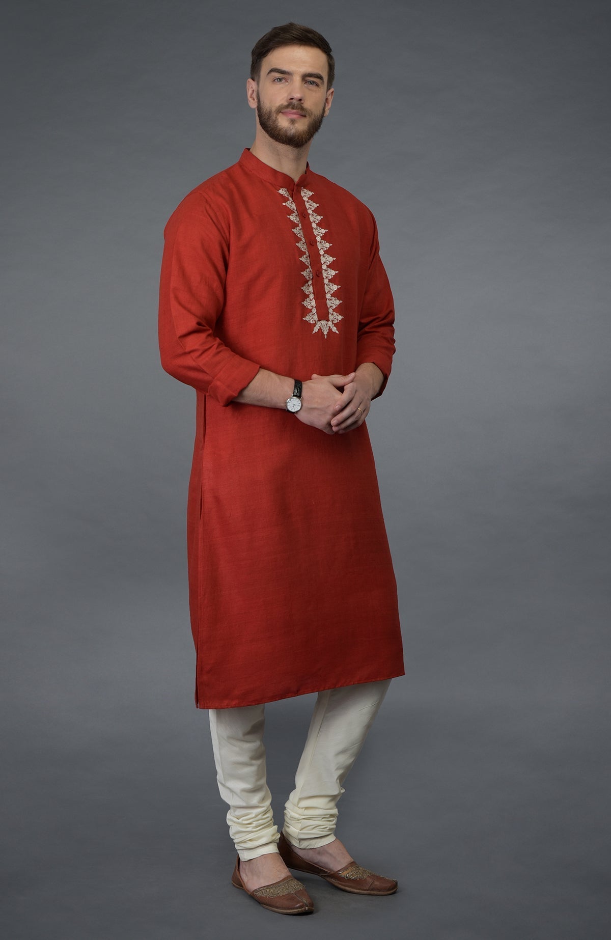 A man wears a red pure silk kurta with floral embroidery and ivory lowers.