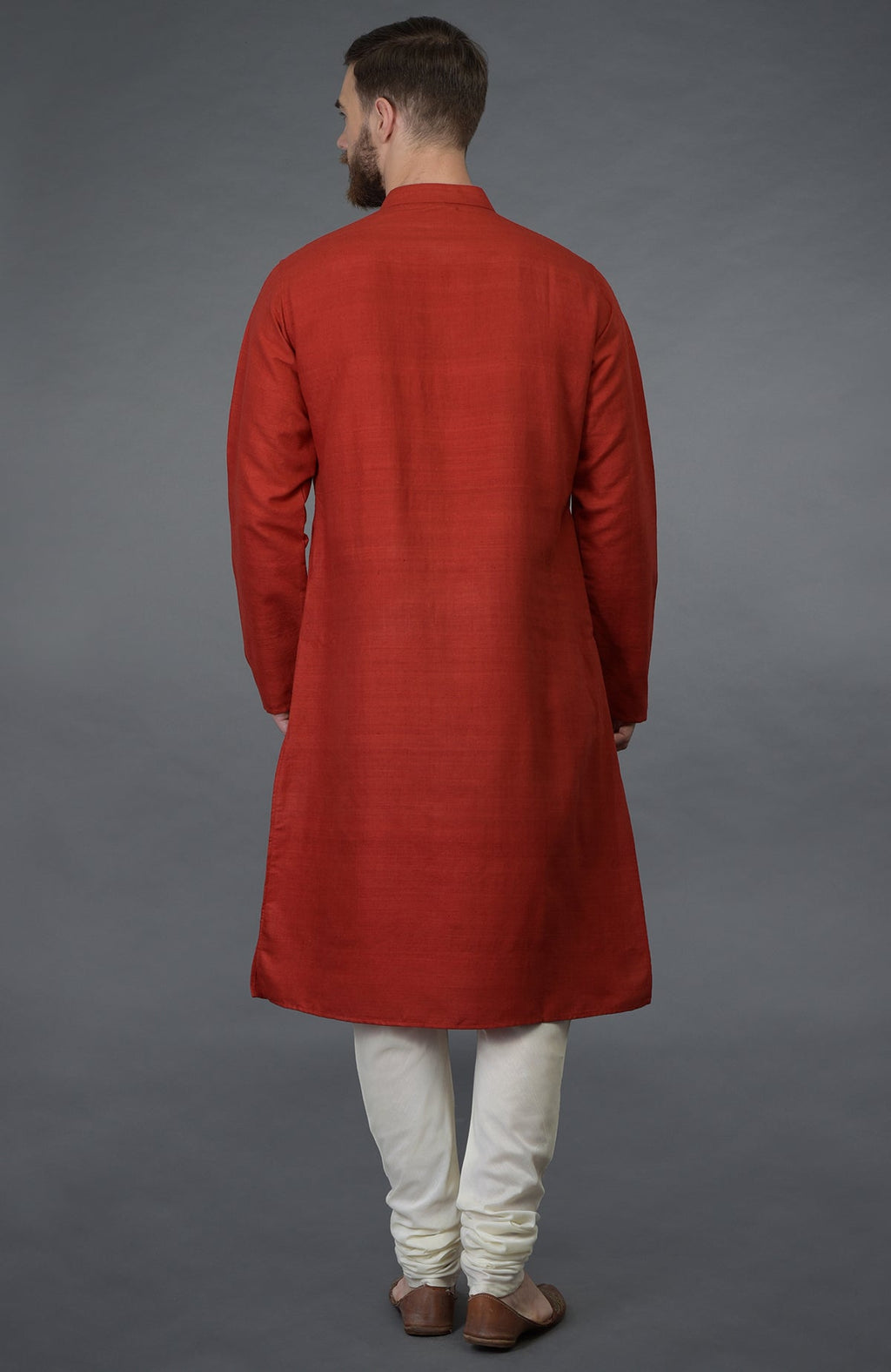 A man from behind wearing a red pure silk kurta and ivory churidar.