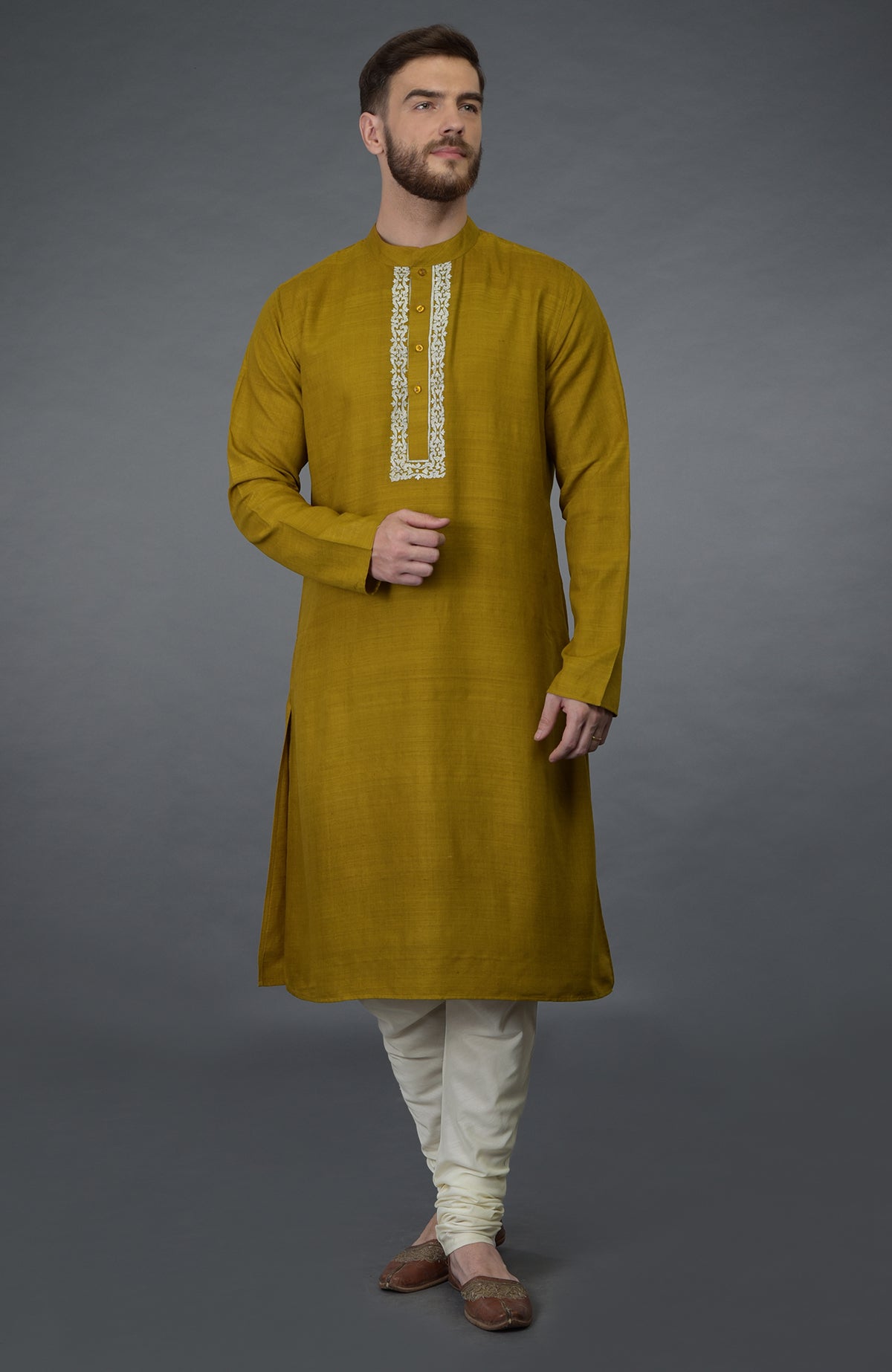 Mustard pure silk kurta with embroidered placket detail, paired with ivory churidars and juttis.