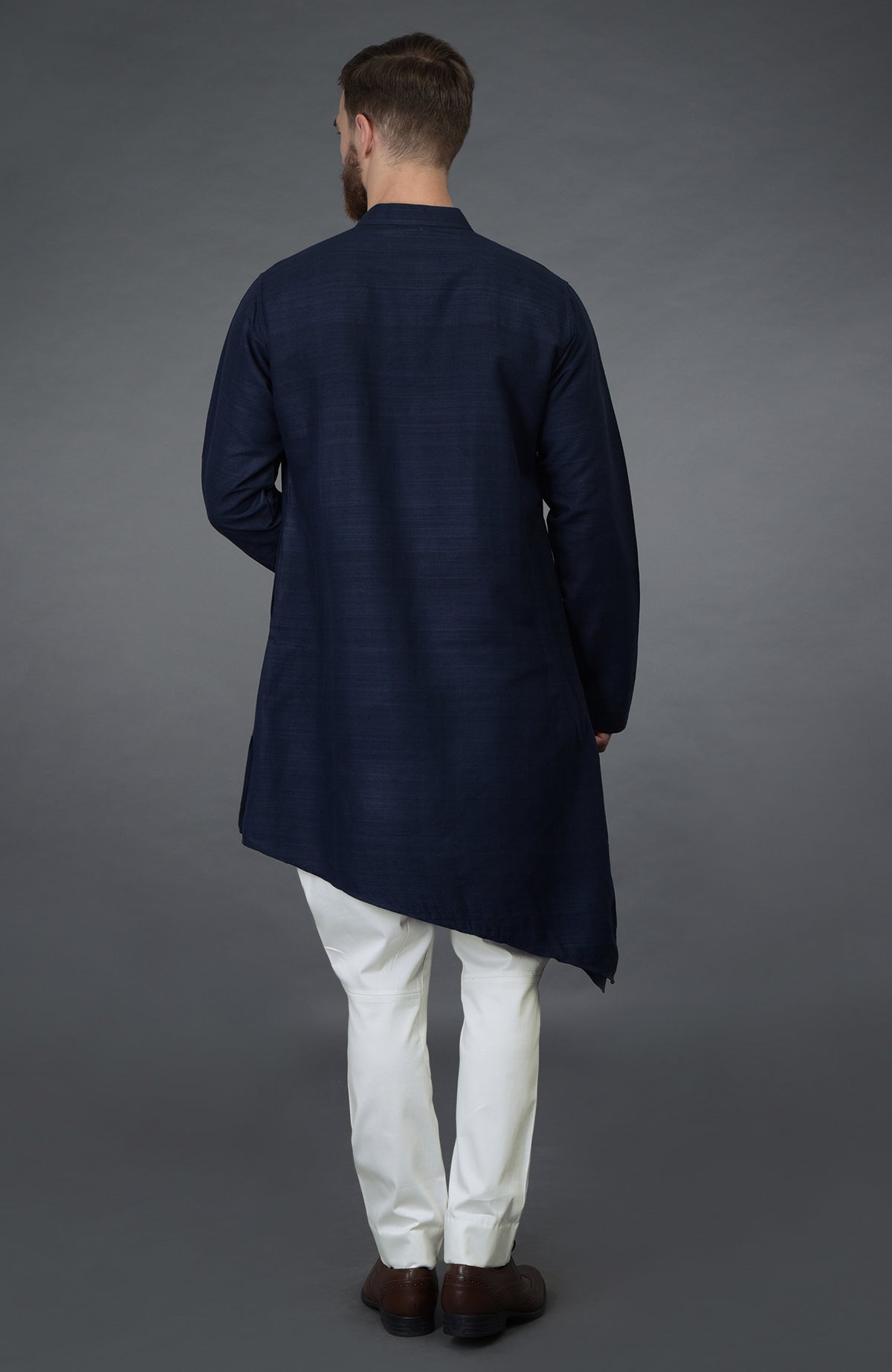 A man from behind wears a navy blue asymmetric kurta and white breeches.