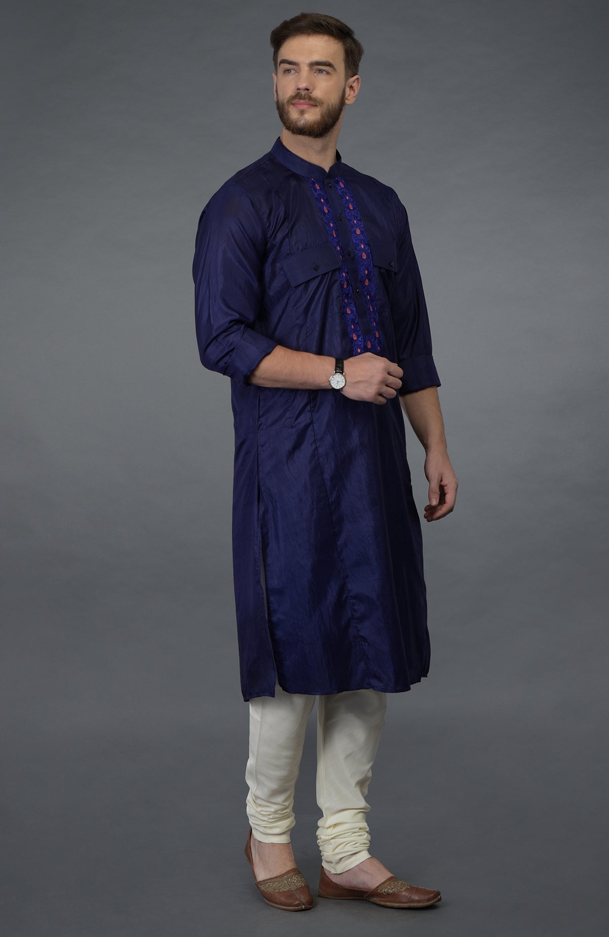 An ink blue silk kurta with an embroidered placket, paired with ivory churidars and brown juttis.