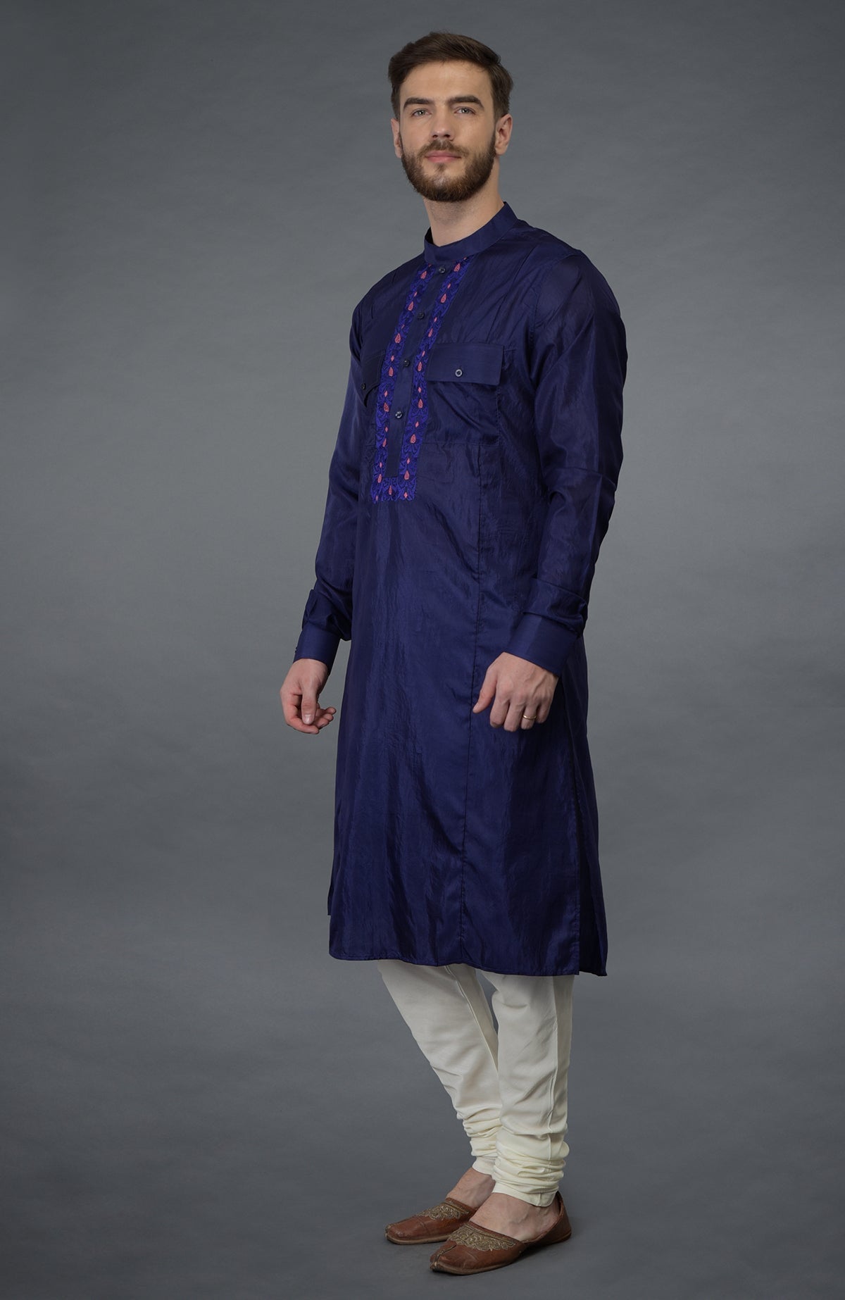 An ink blue embroidered silk kurta set with ivory lowers and brown shoes.