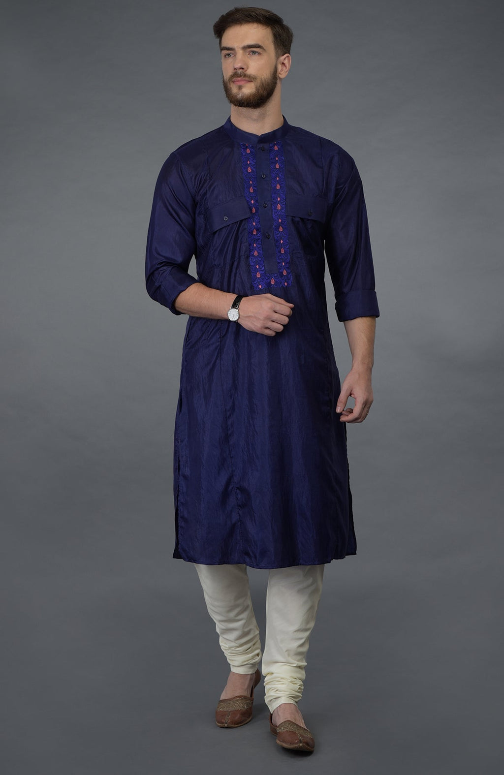 Ink blue silk kurta with embroidered placket, ivory churidar, and brown juttis.