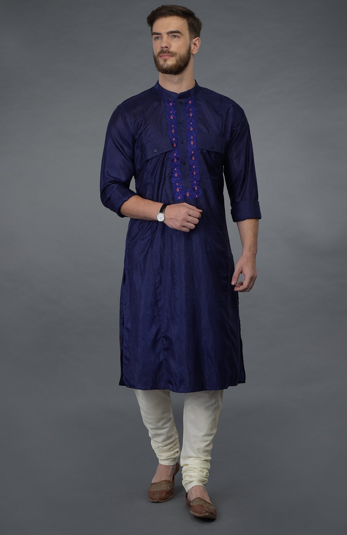Ink blue silk kurta with embroidered placket, ivory churidar, and brown juttis.