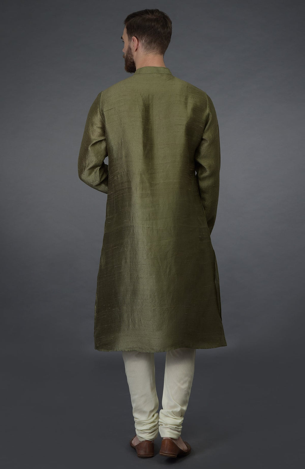 A man from behind wears an olive green kurta and ivory churidar pants.
