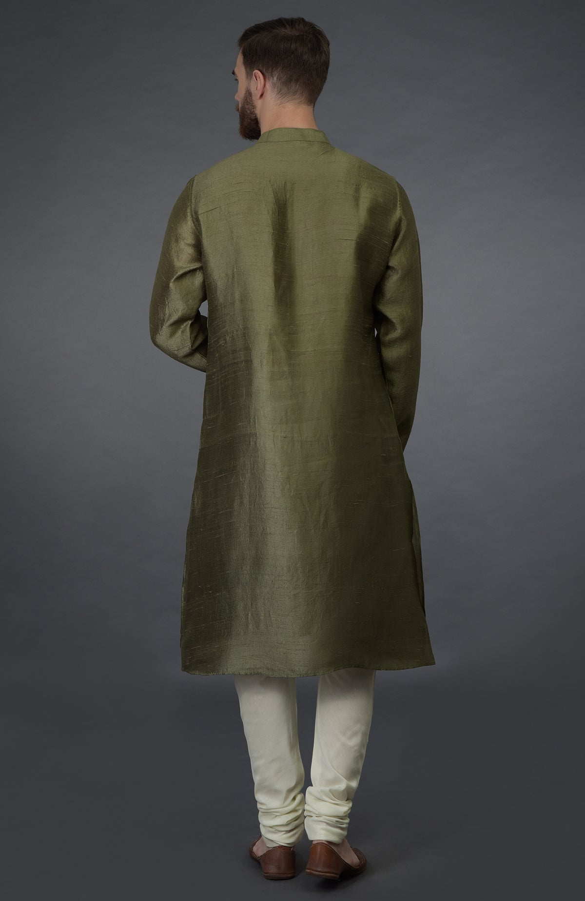 A man from behind wears an olive green kurta and ivory churidar pants.