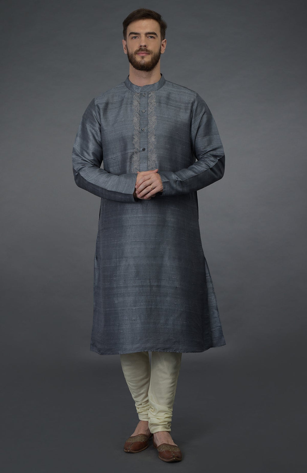 A man models a grey pure silk kurta with an embroidered placket and ivory churidars.