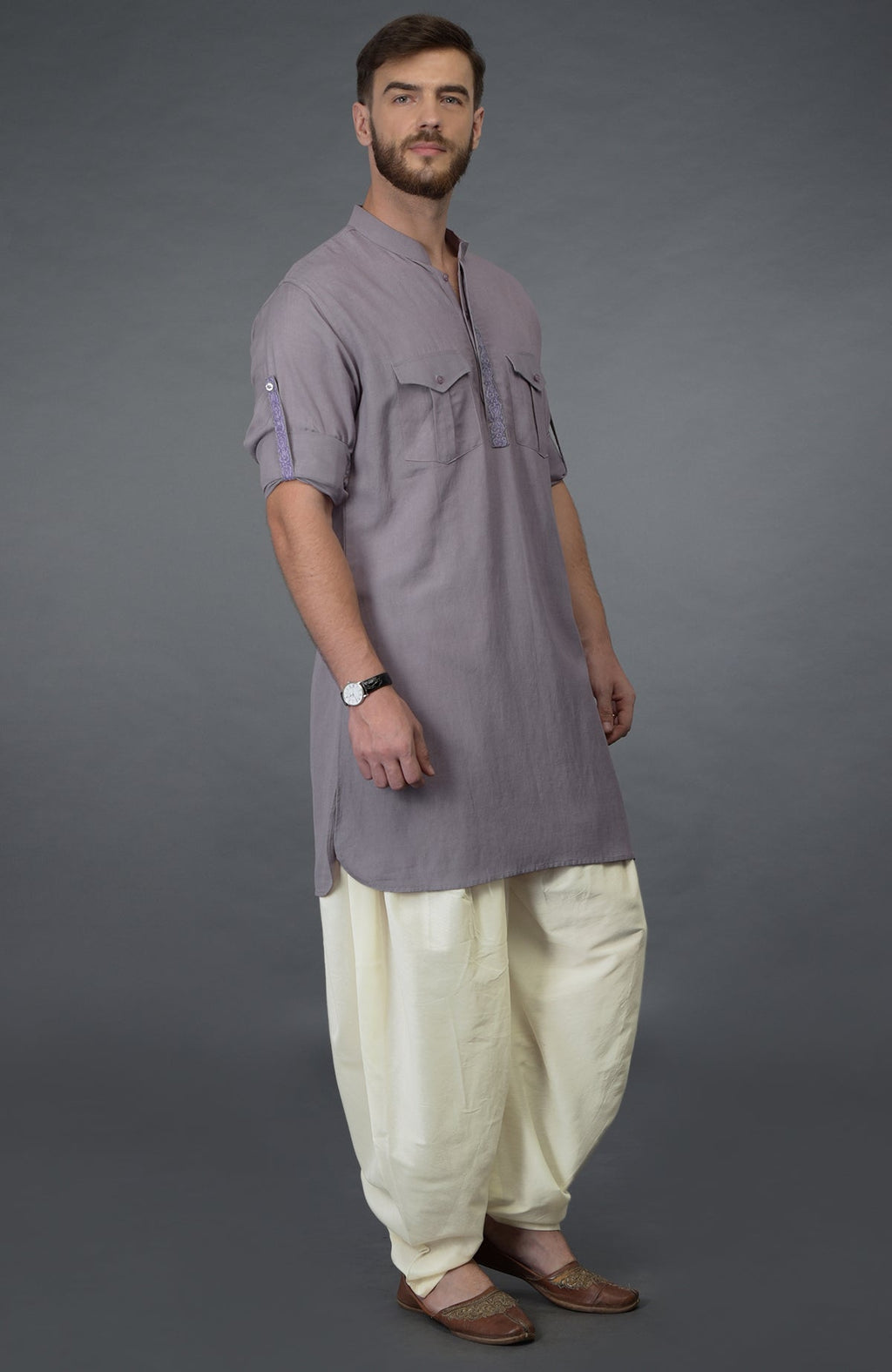 A man models a lilac grey embroidered linen kurta with ivory pathani salwar pants.