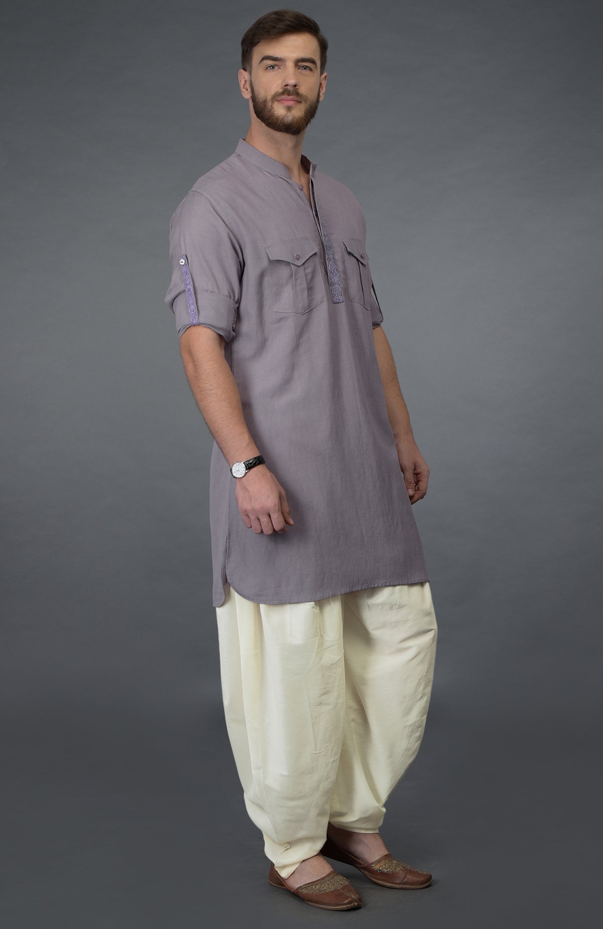 A man models a lilac grey embroidered linen kurta with ivory pathani salwar pants.