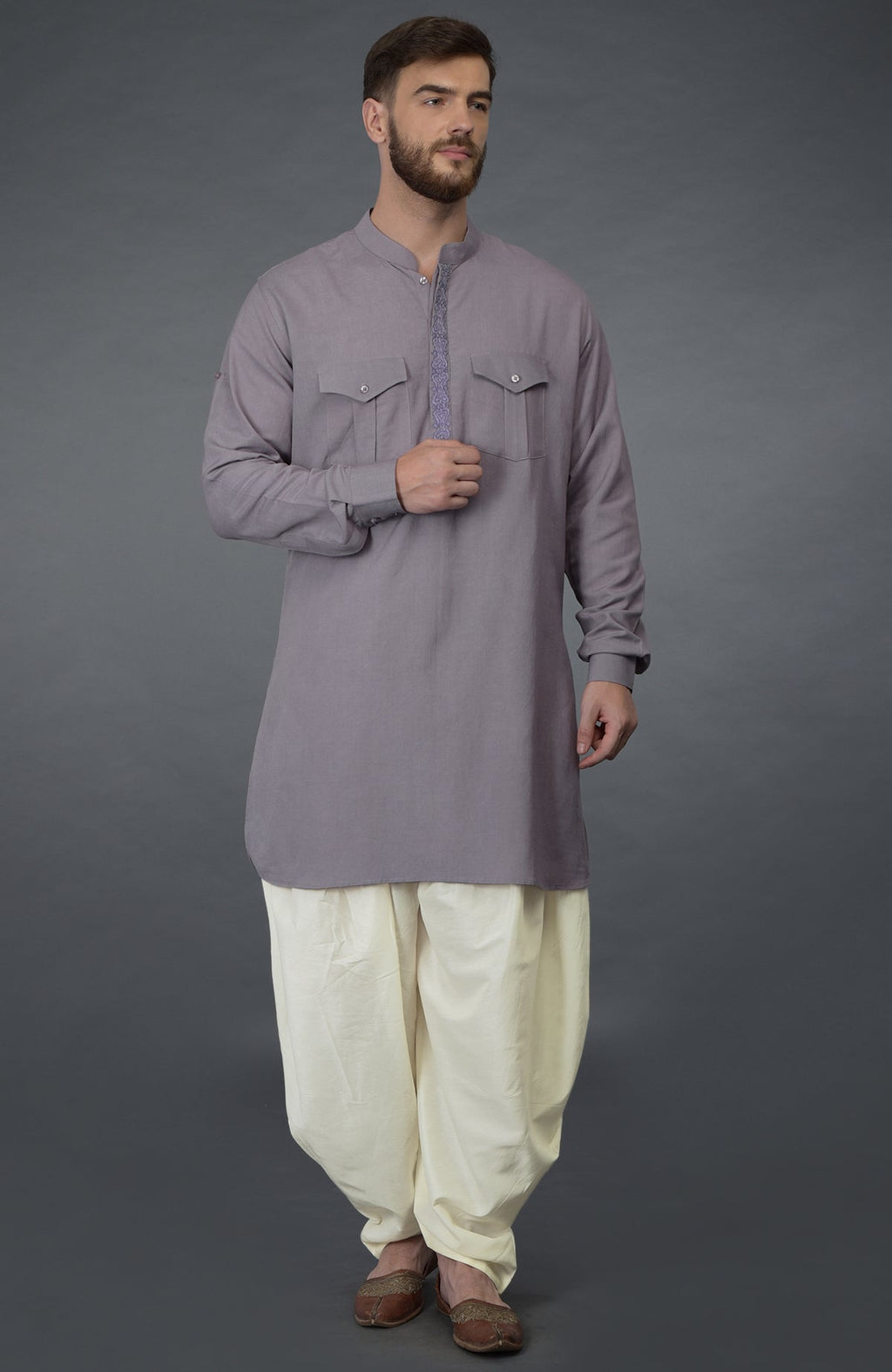 A man models a lilac grey embroidered linen kurta with ivory pathani salwar pants.