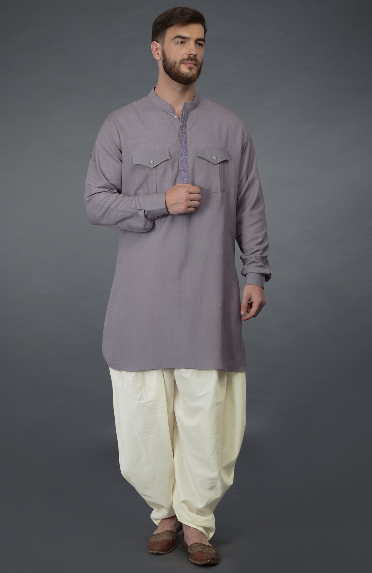 A man models a lilac grey embroidered linen kurta with ivory pathani salwar pants.