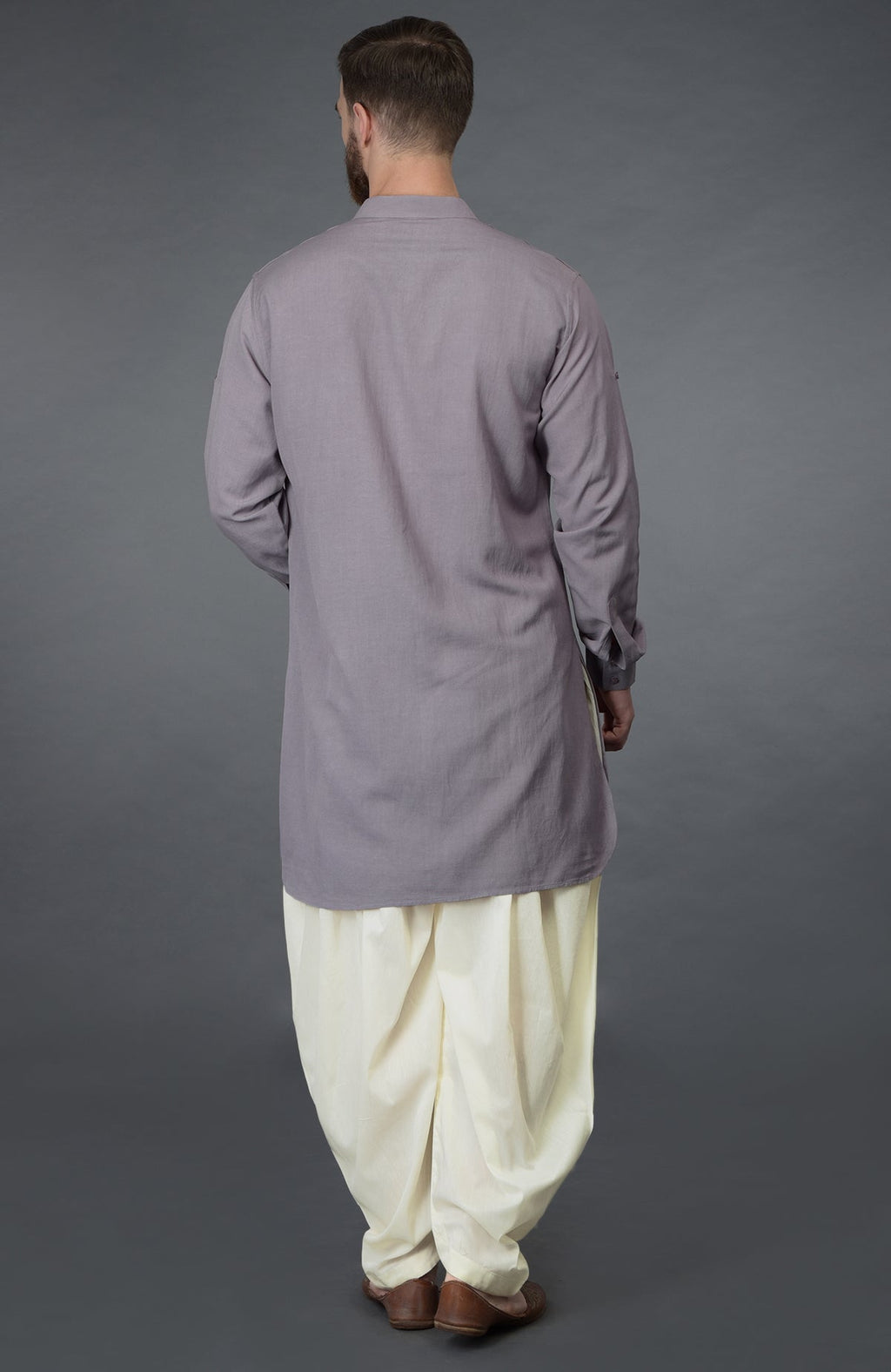 A man from behind wears a lilac grey kurta and ivory pathani salwar pants.