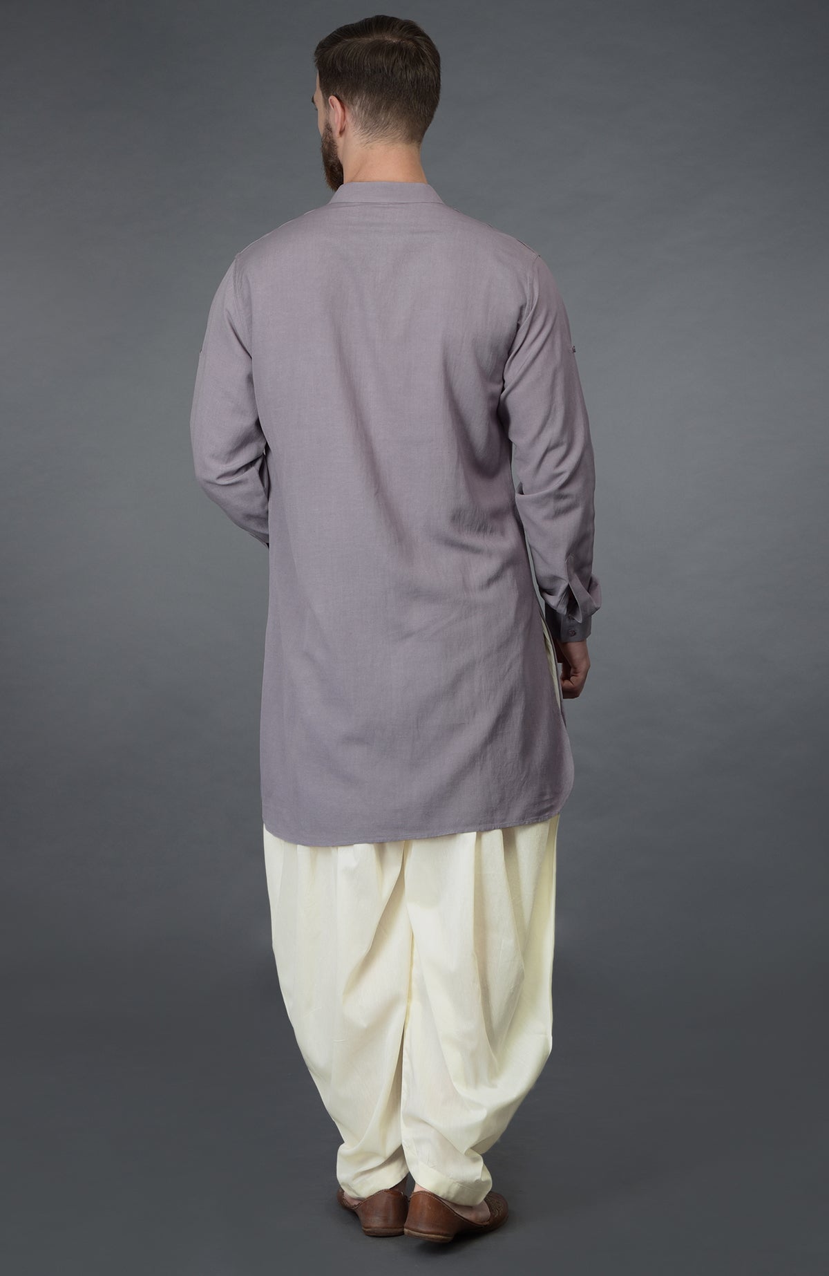 A man from behind wears a lilac grey kurta and ivory pathani salwar pants.