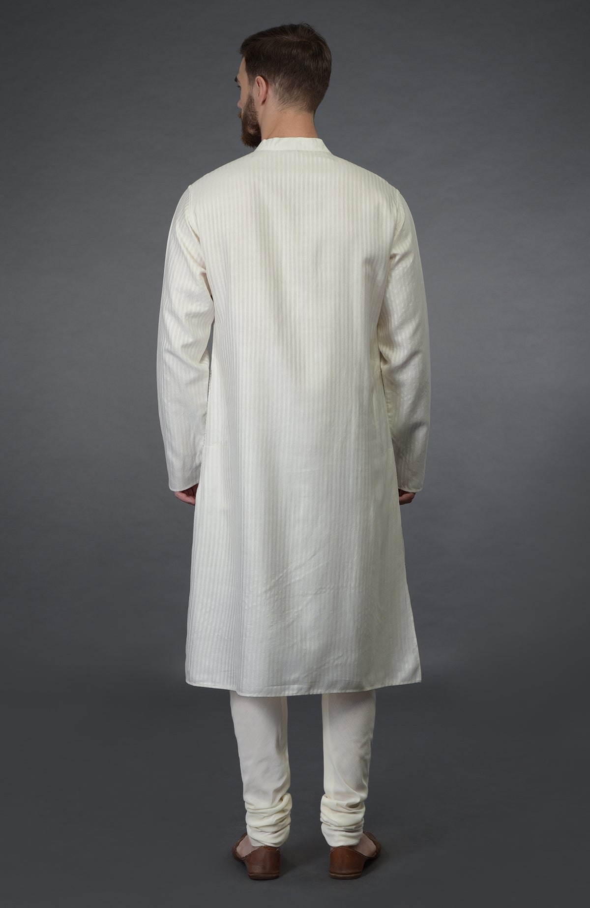 A man from behind wears an ivory self-weave striped silk kurta and matching churidars.