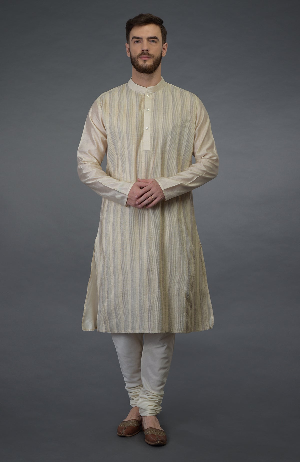 A man models a cream pure silk kurta with pintuck detail and matching churidar.