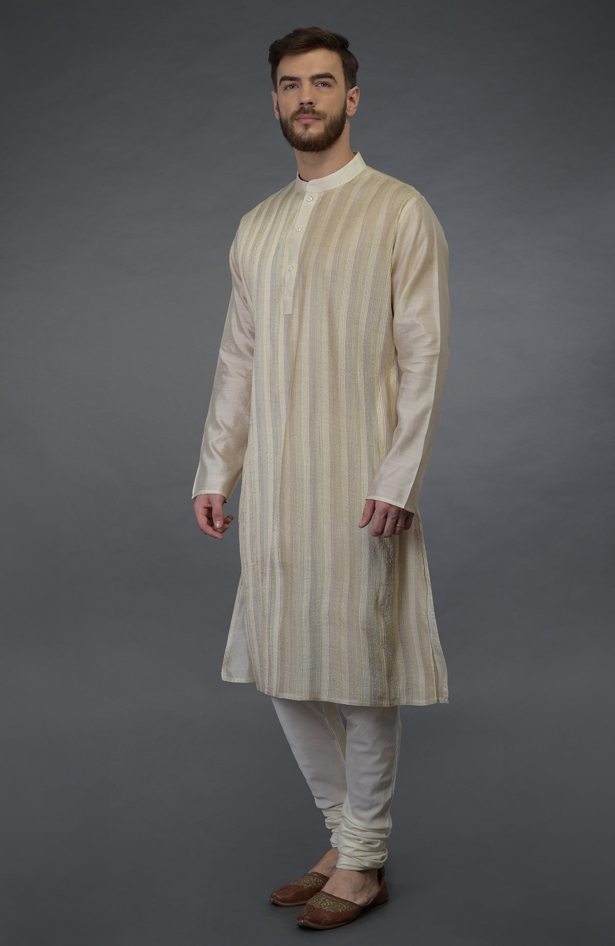 A man models a cream pure silk kurta with pintuck detail and cream lowers.