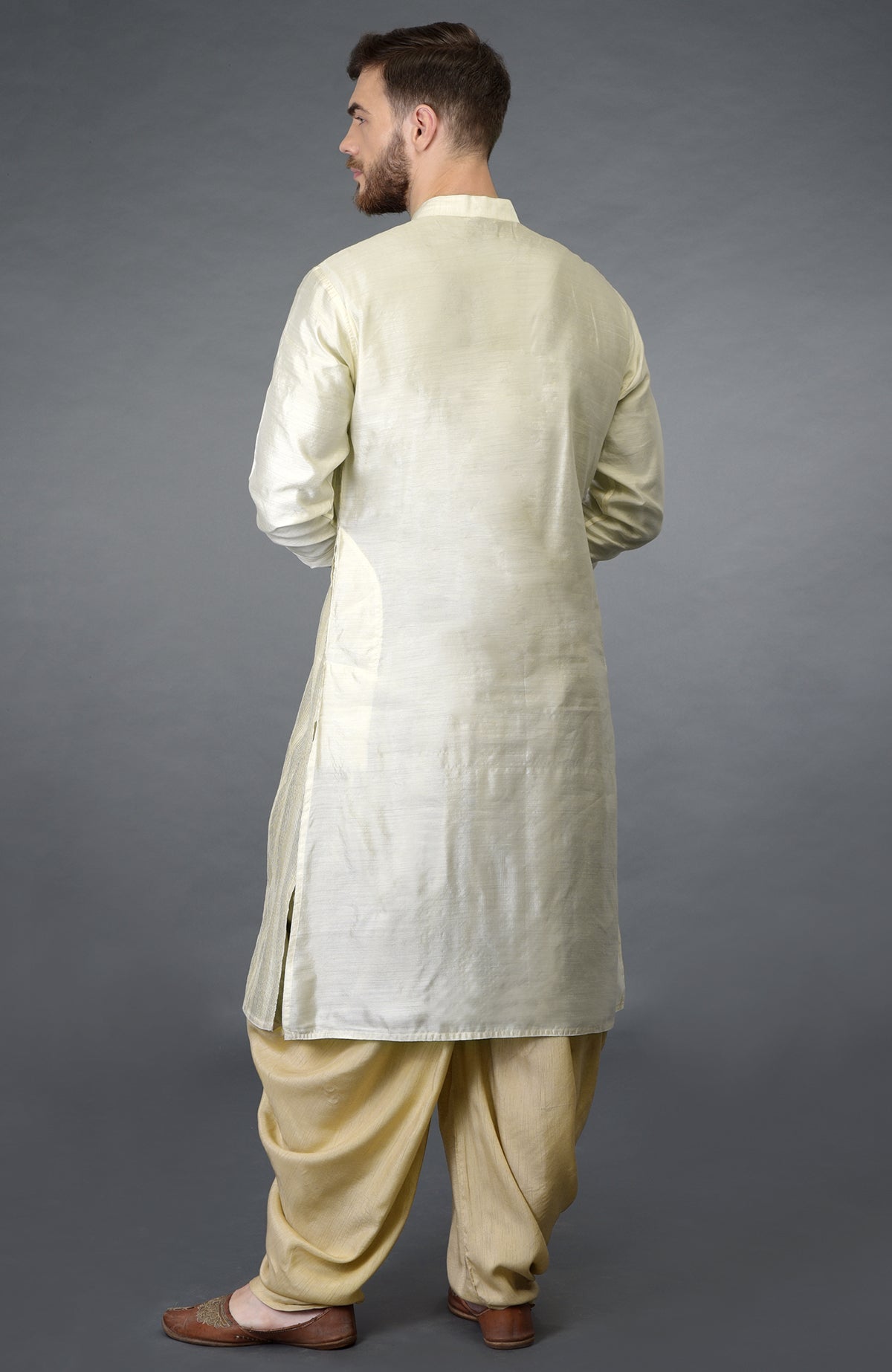 A man from behind wearing a cream pintuck pure silk kurta set with brown shoes.