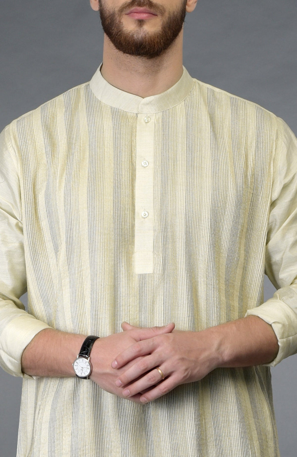 A man wears a cream pintuck pure silk kurta with a watch and ring.