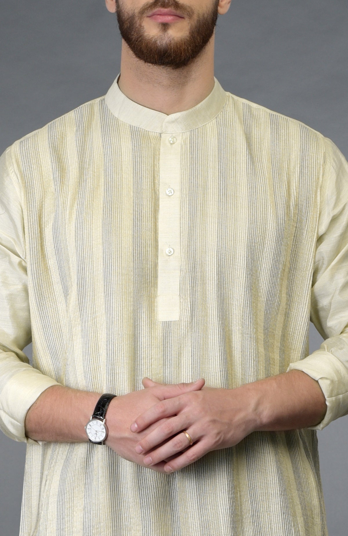 A man wears a cream pintuck pure silk kurta with a watch and ring.