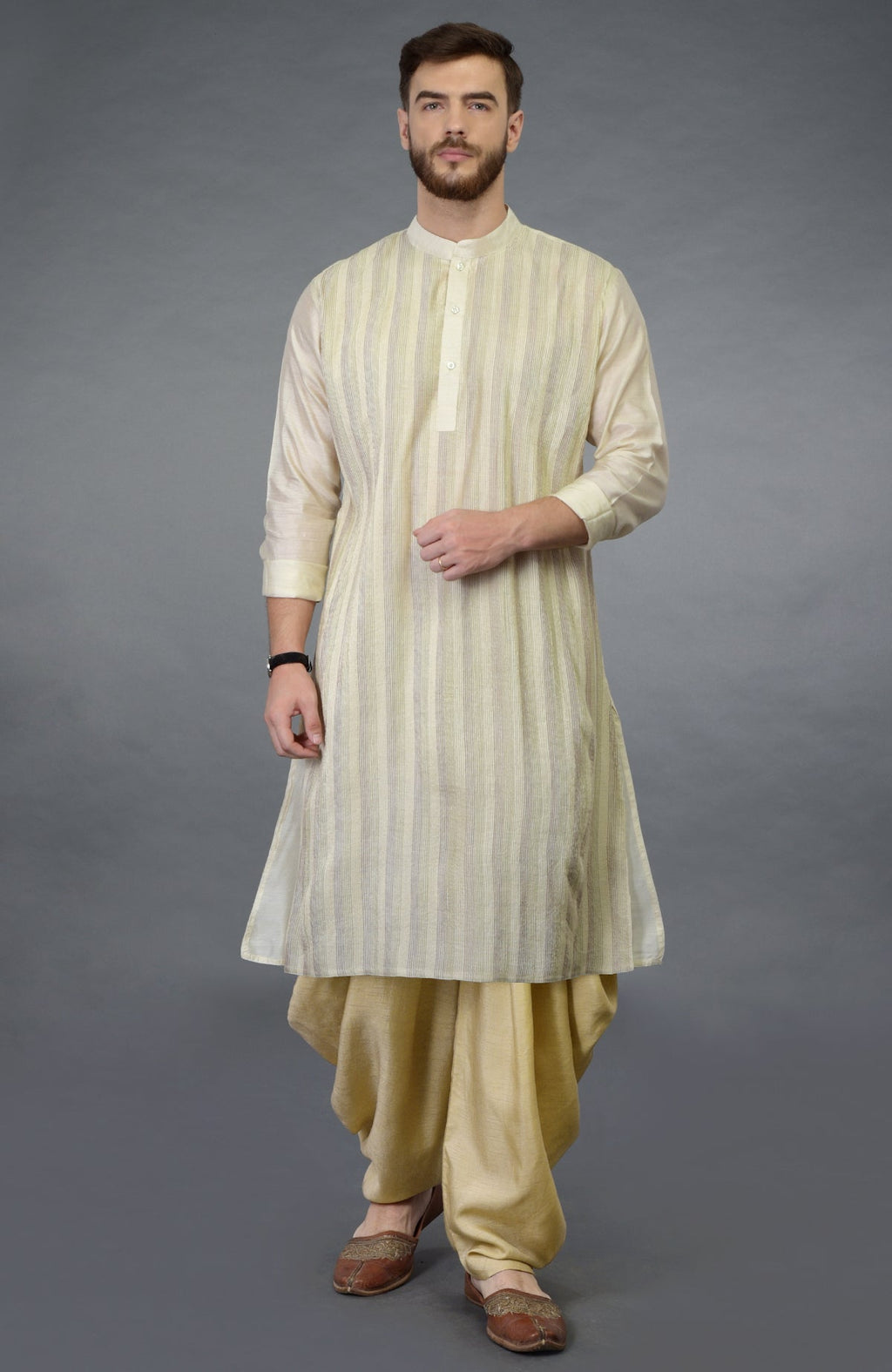A man models a cream pintuck pure silk kurta set with a dhoti salwar.