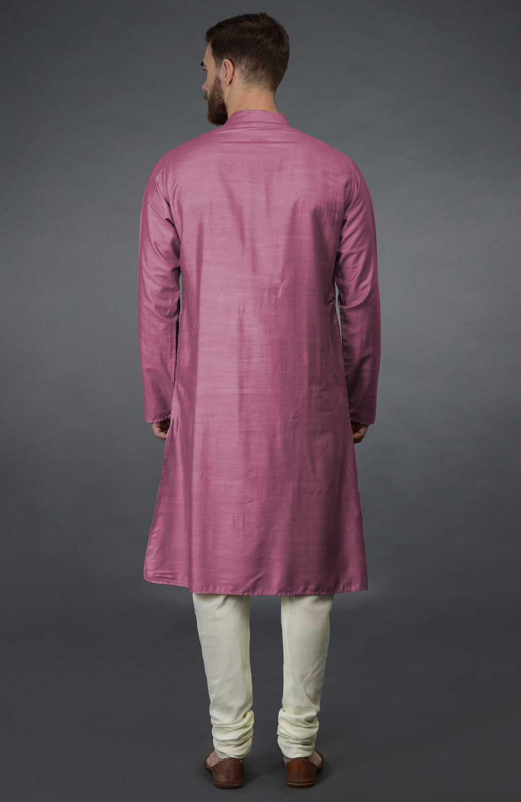 Rear view of a man wearing a wine kurta and ivory churidar pants.