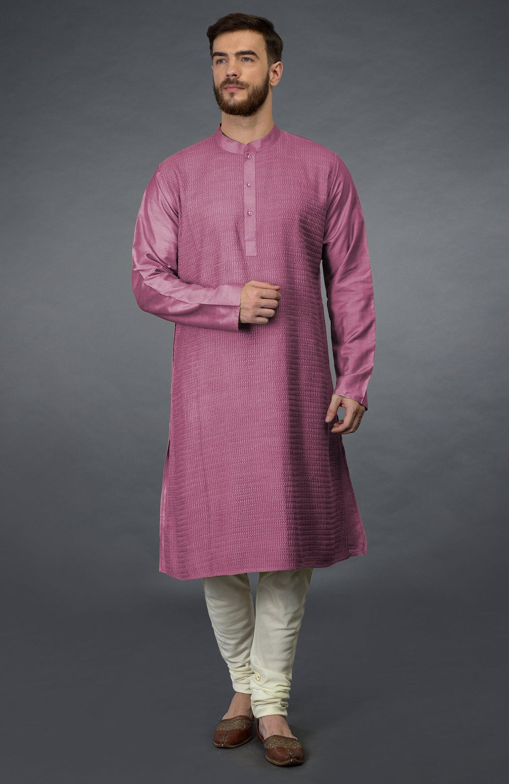 A man in a wine-colored kurta with pintuck details and ivory churidars.