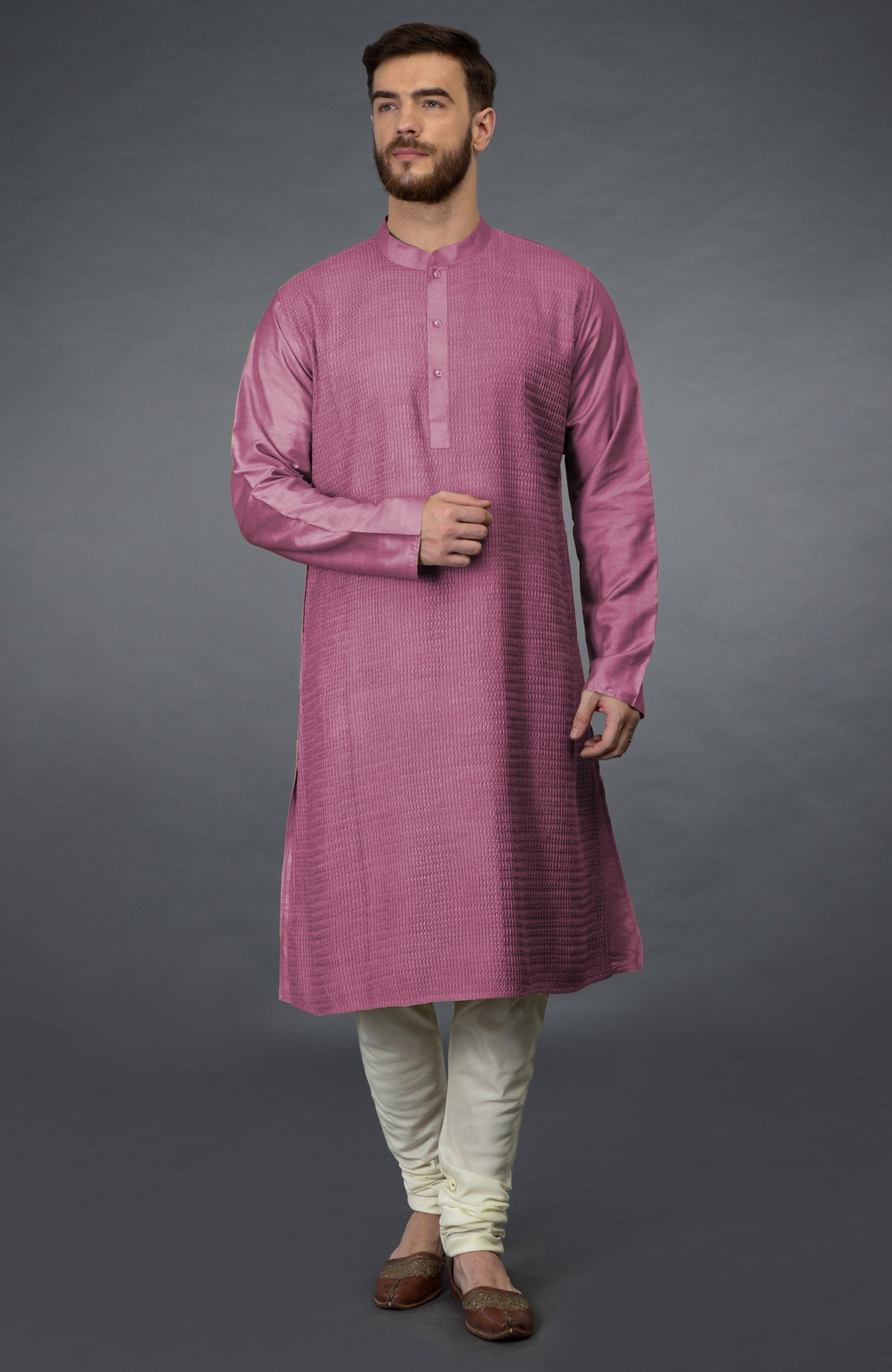 A man in a wine-colored kurta with pintuck details and ivory churidars.