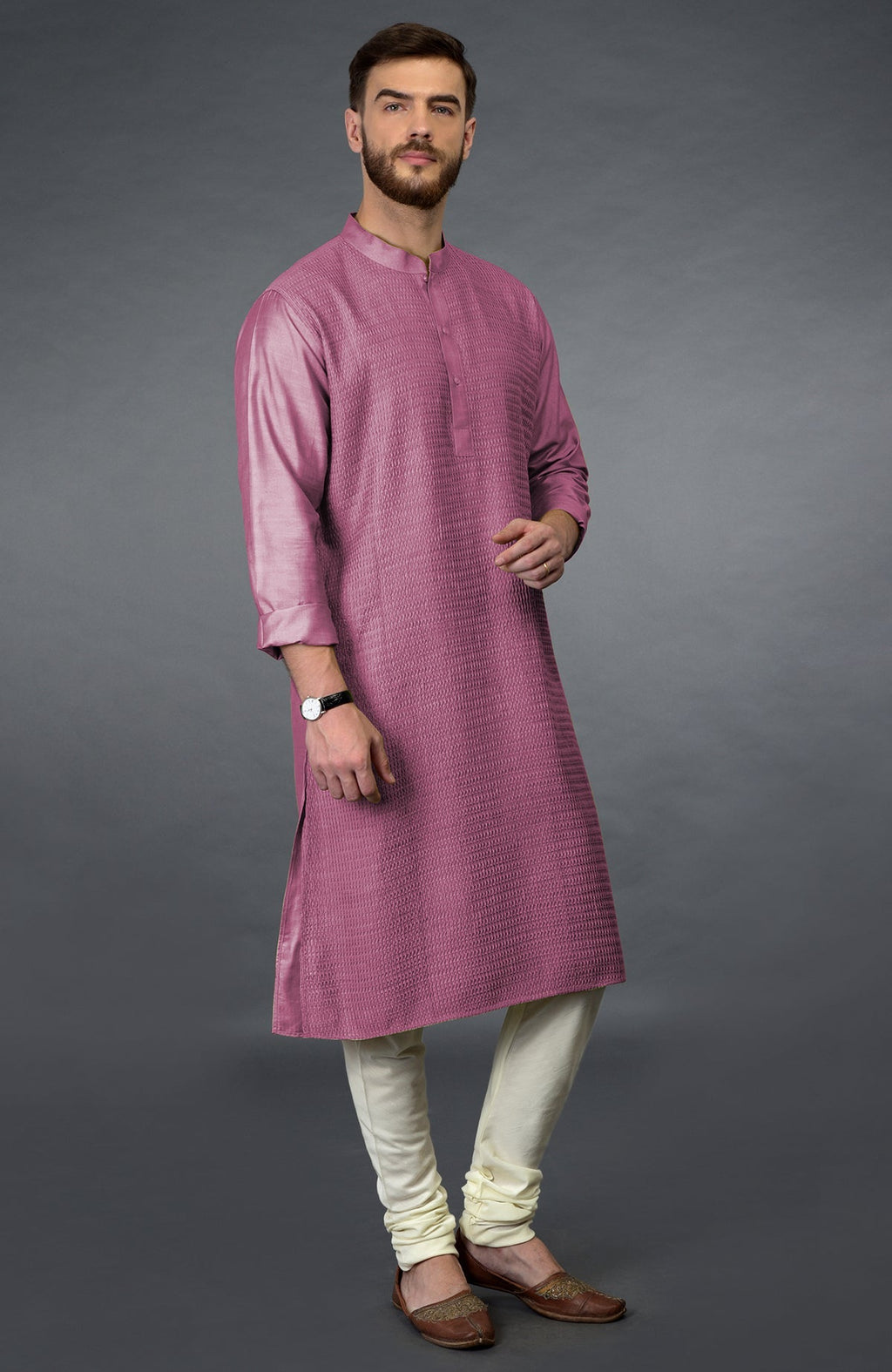 A man models a wine pintuck kurta set with ivory churidar pants and brown juttis.