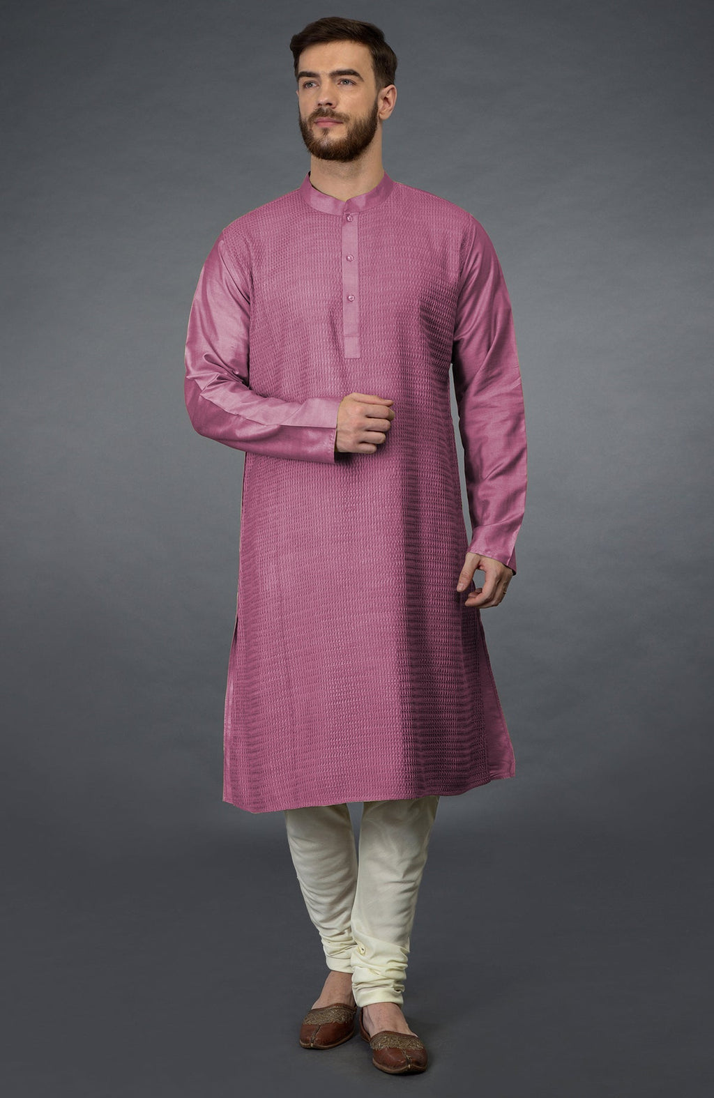 A man models a wine pintuck kurta with ivory churidar pants and brown juttis.