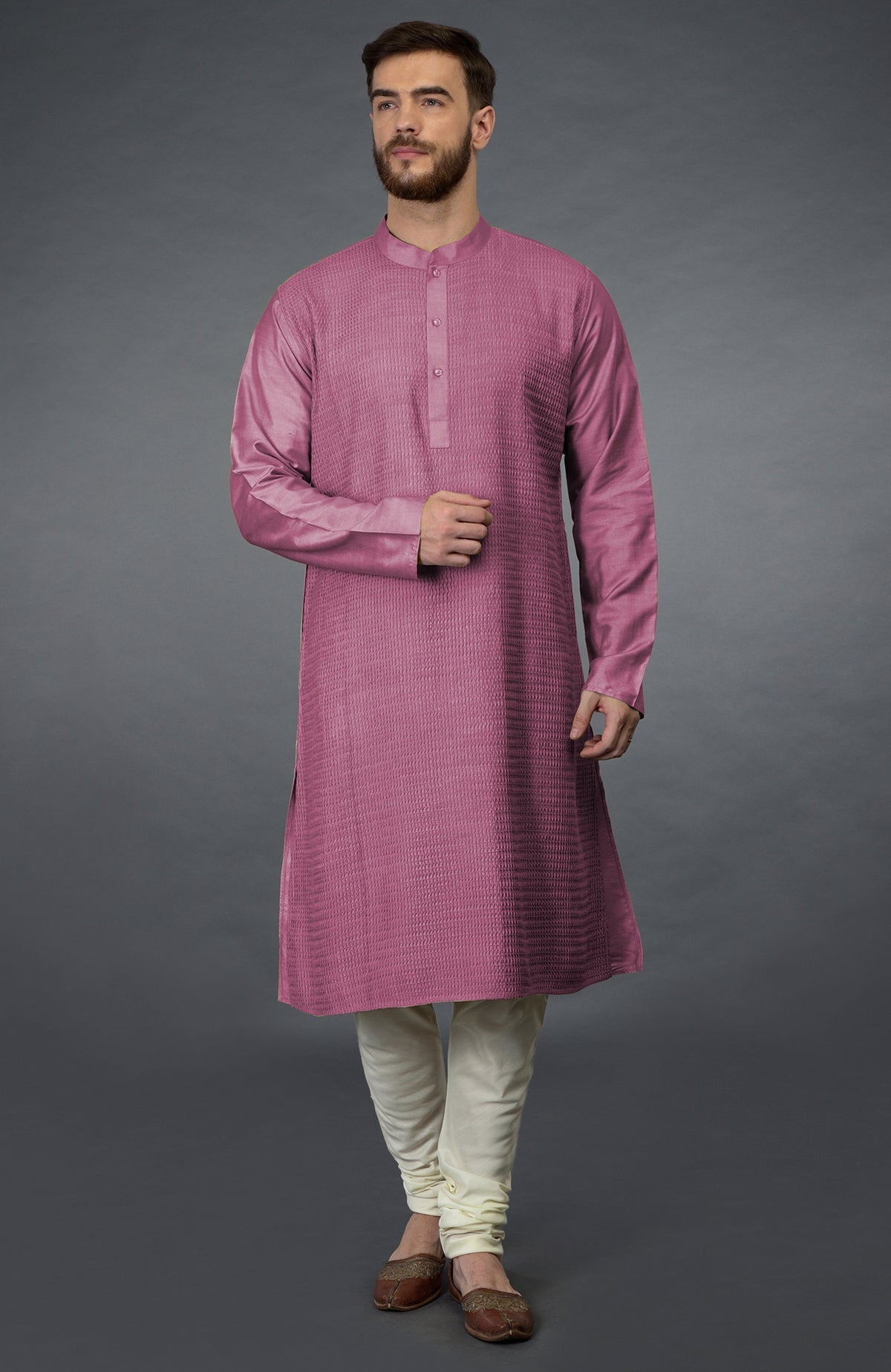 A man models a wine pintuck kurta with ivory churidar pants and brown juttis.