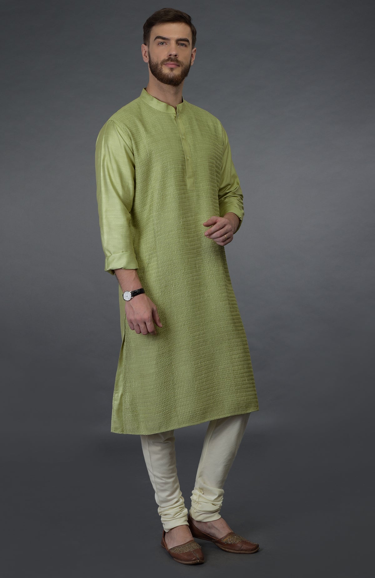 Pista green pintuck silk kurta with cream churidar pants and brown juttis.