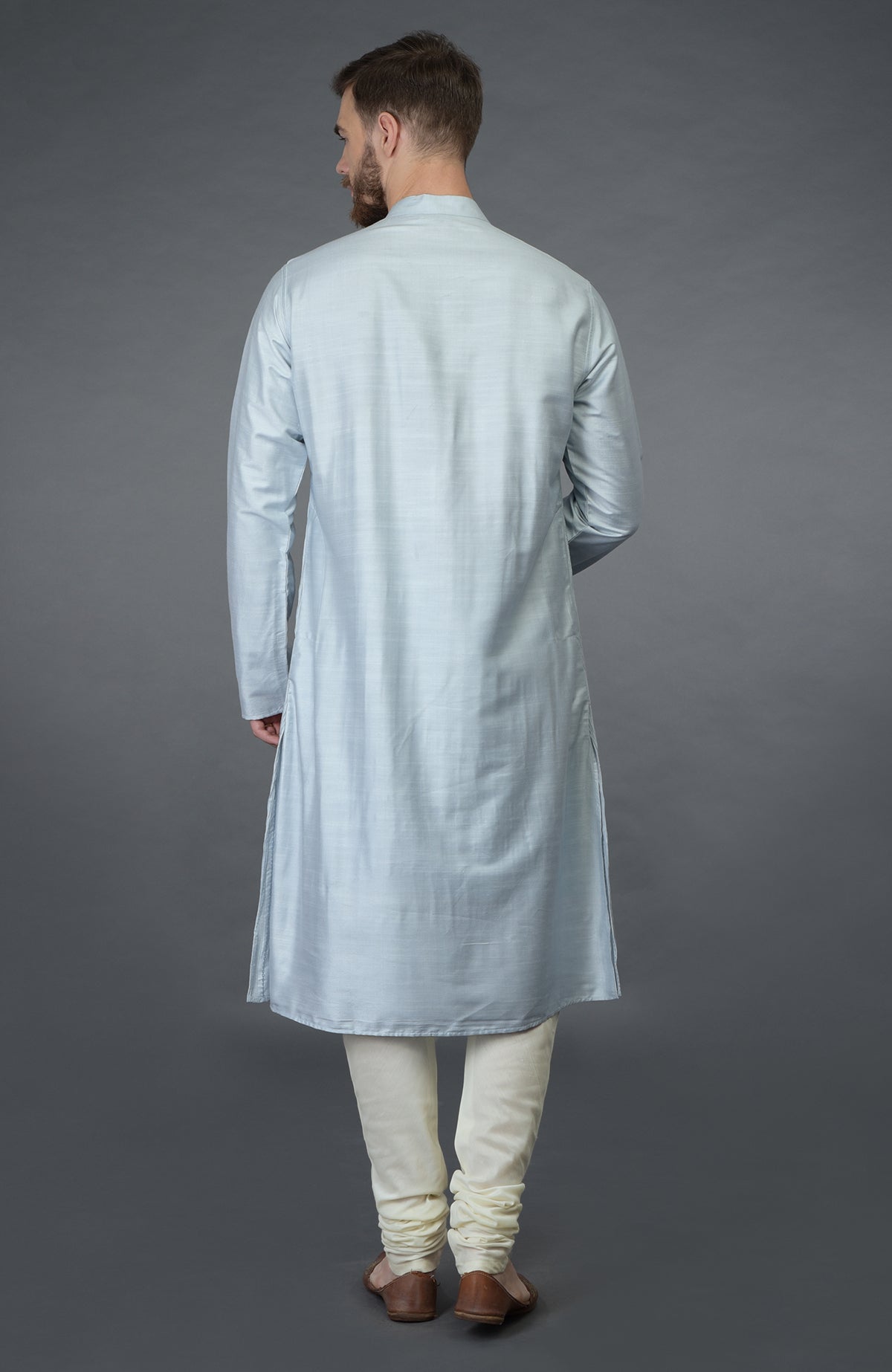 A man from behind wearing a powder blue kurta and ivory churidar pants.