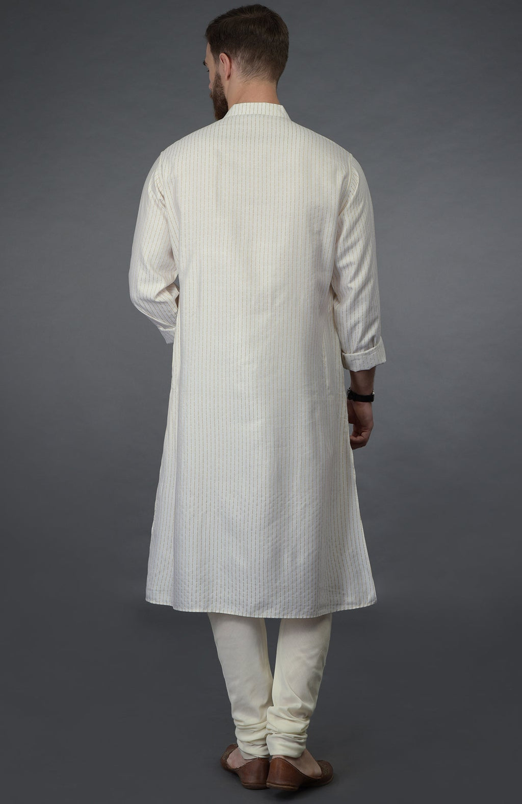 A man from behind wears an ivory silk kurta with pintuck detail and matching churidars.