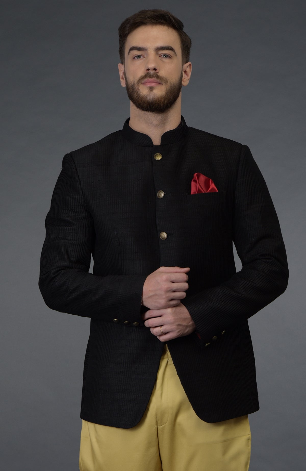 Black pintuck bandhgala jacket set with a red pocket square and camel beige breeches.