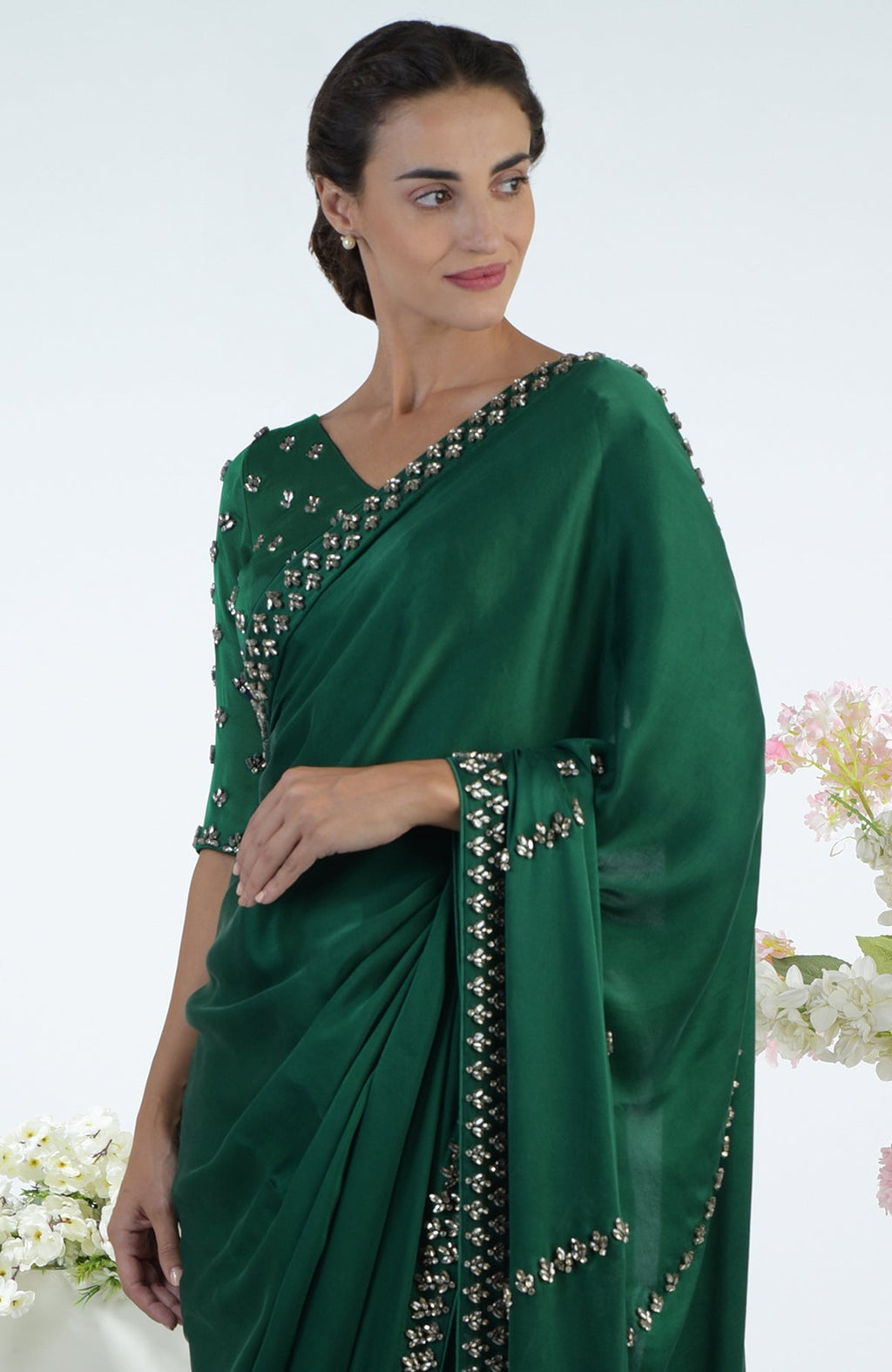 A woman in an emerald green crystal hand-embroidered saree and blouse.
