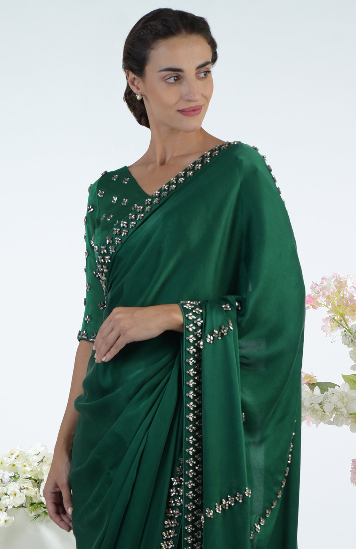 A woman in an emerald green crystal hand-embroidered saree and blouse.