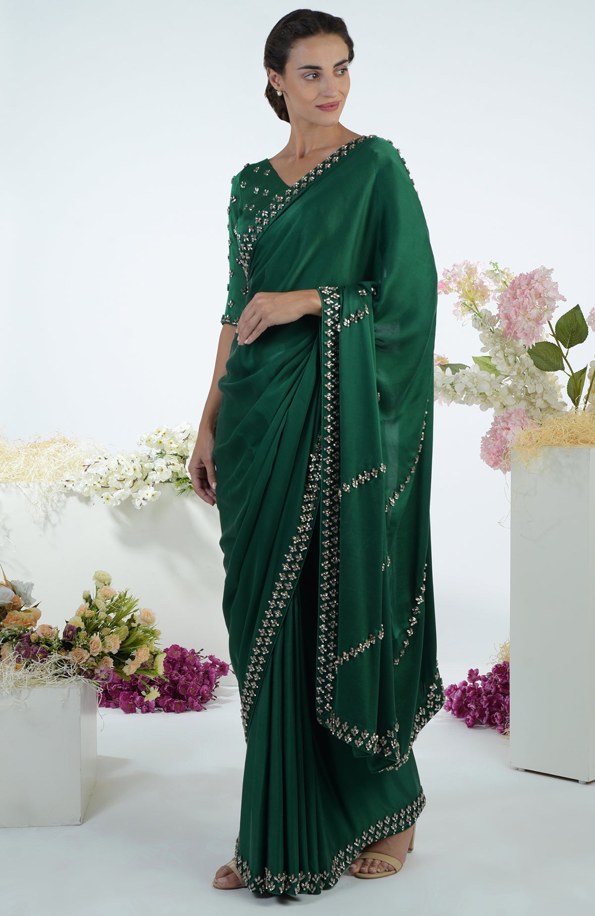 An elegant woman models an emerald green crystal hand-embroidered saree and blouse.