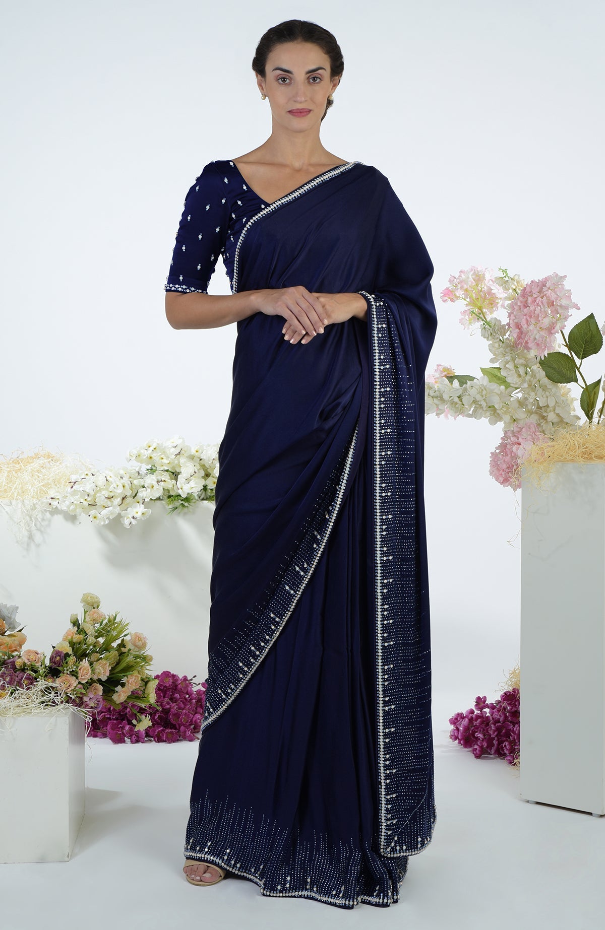 A woman models a midnight blue crystal hand-embroidered saree and blouse.