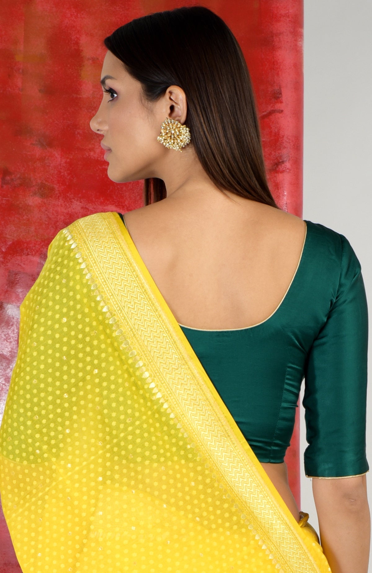 A woman models an emerald green blouse with a yellow sari.
