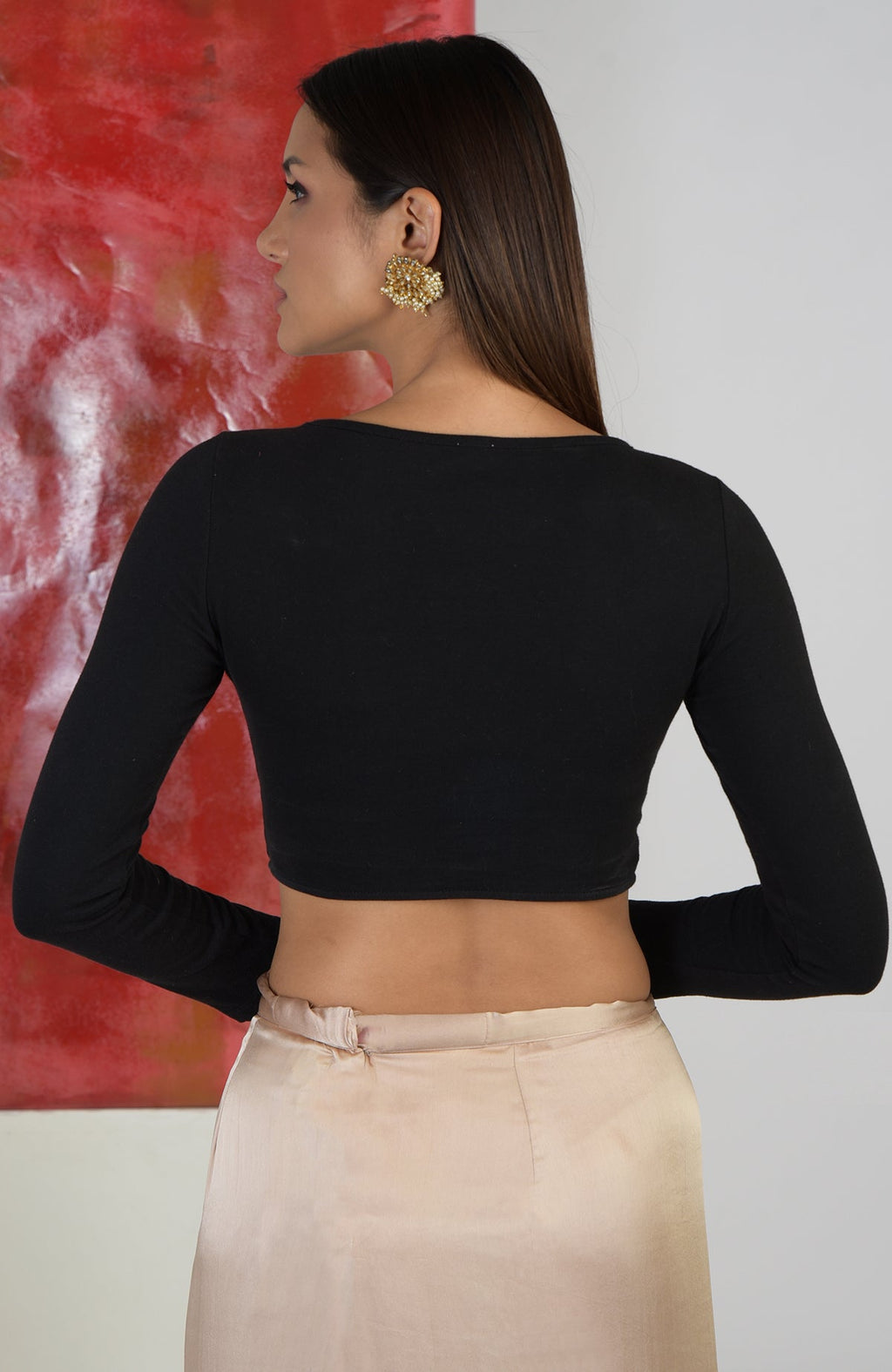 Black boat neck blouse with long sleeves paired with a light gold skirt.