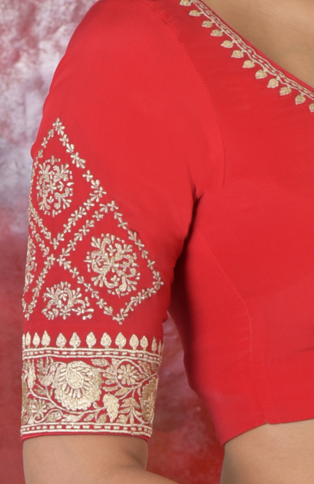 Red silk blouse with gold zari embroidery on the sweetheart neckline and sleeves.