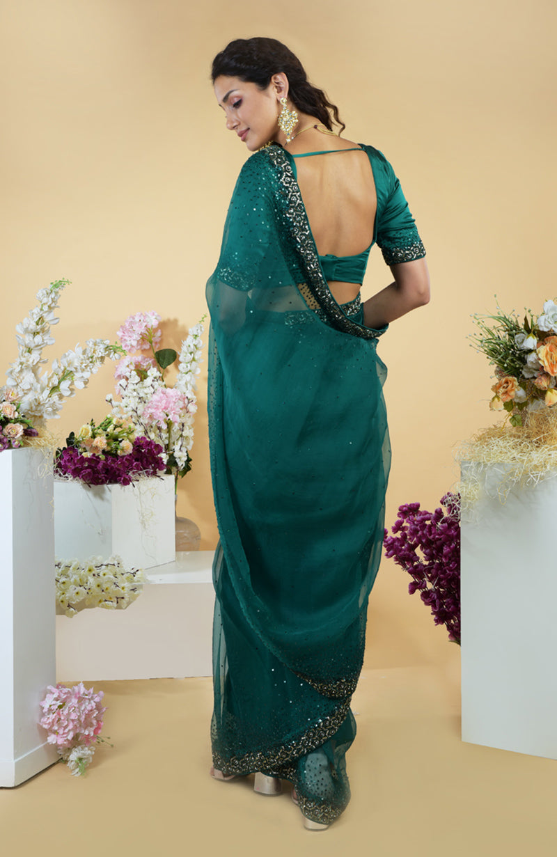 Emerald green organza saree with beads and sequin embroidery, draped on a model from the back.