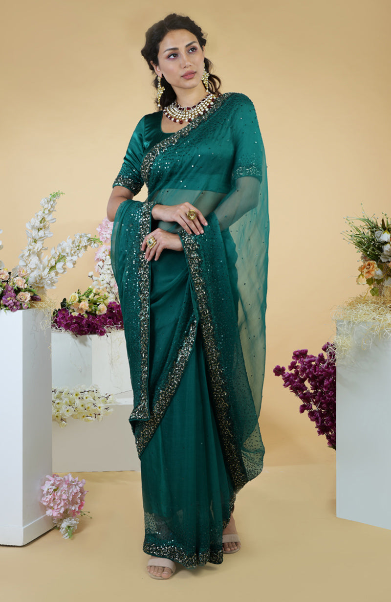 An emerald green organza saree with bead and sequin embroidery is worn by a woman.