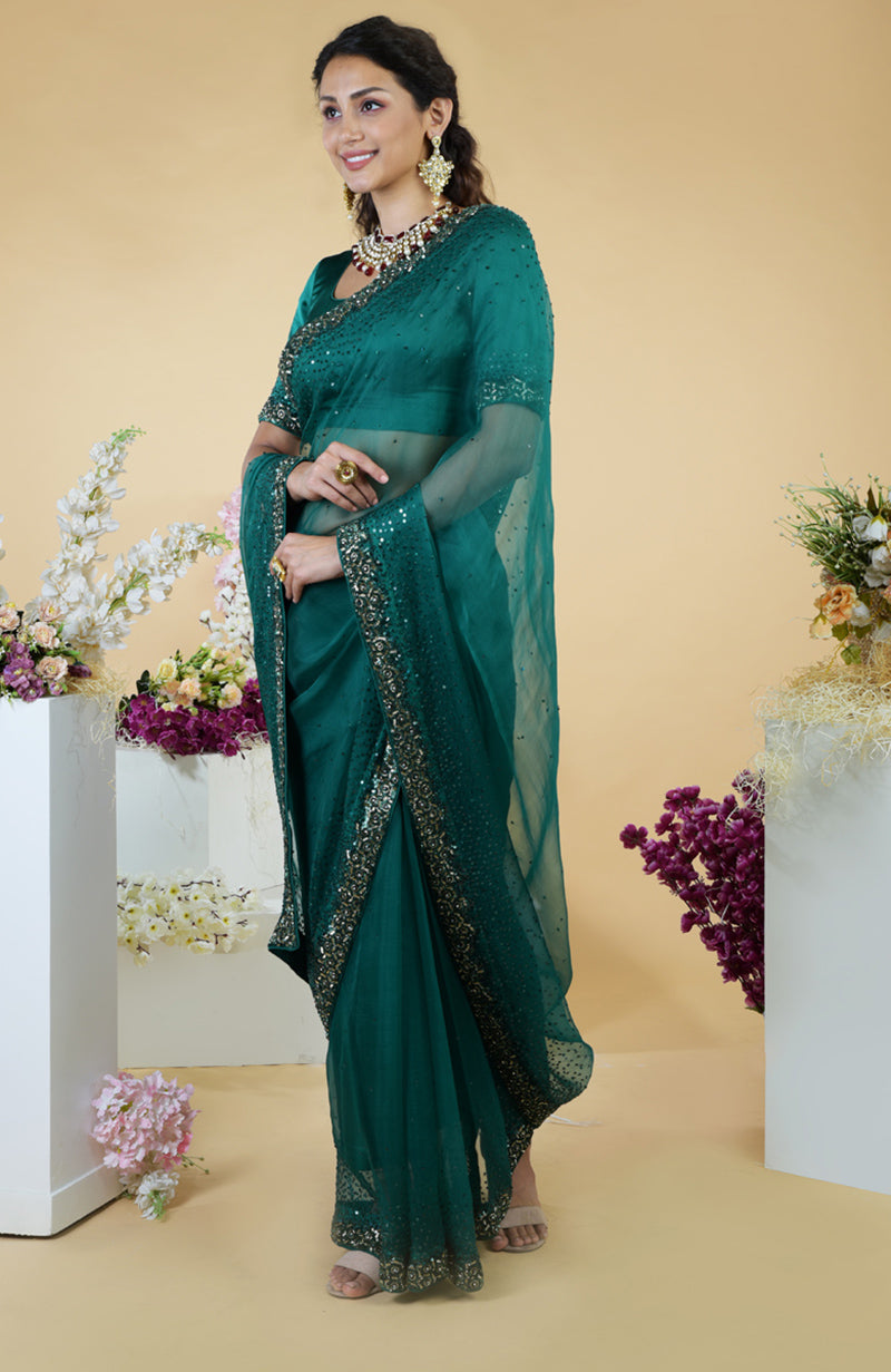 An emerald green organza saree with bead and sequin embroidery is worn by a woman.