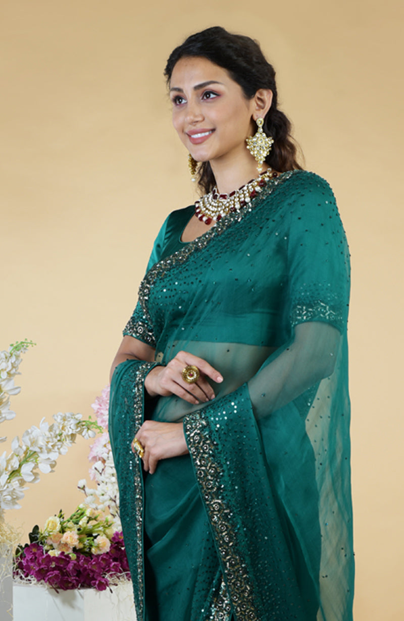An emerald green organza saree with bead and sequin embroidery.
