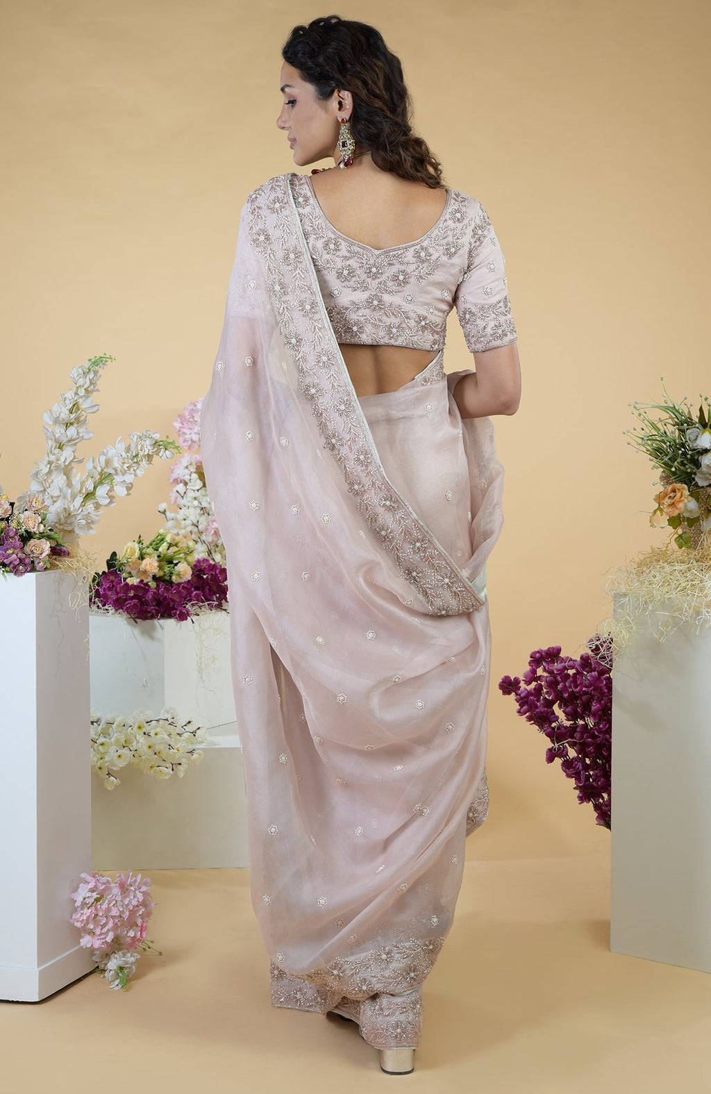 A woman from the back wears a nude pink hand-embroidered silk organza saree.